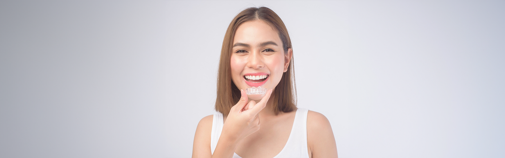 Cute girl holding Invisalign and smiling