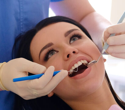 Dentist checking girl mouth using dental tool