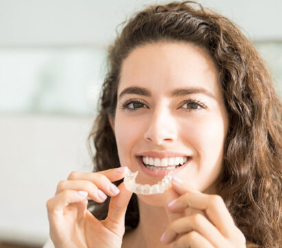 girl holding Invisalign in her hand and smiling