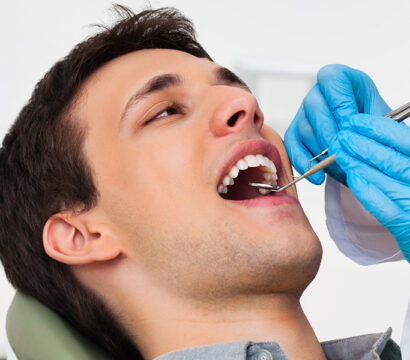 dentist is treating guy mouth with dental equipment